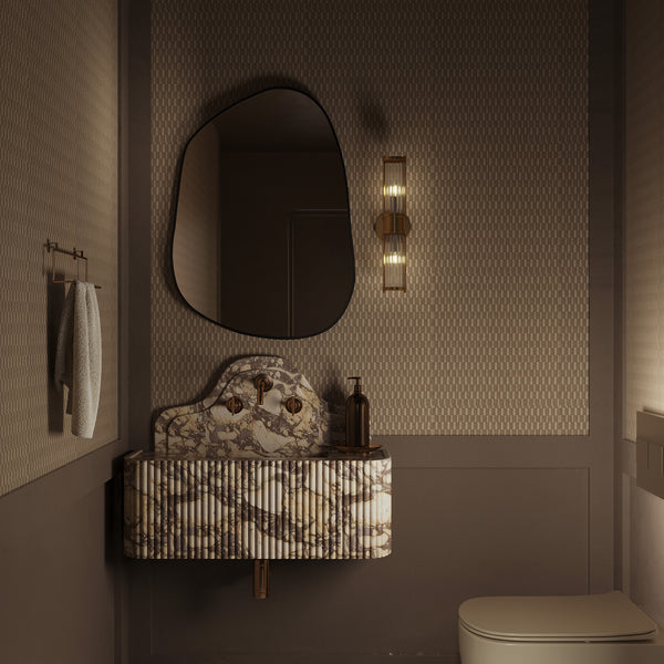 Bathroom vanity with a marble sink, textured walls, an organic-shaped wall mirror, and a vertical wall sconce.
