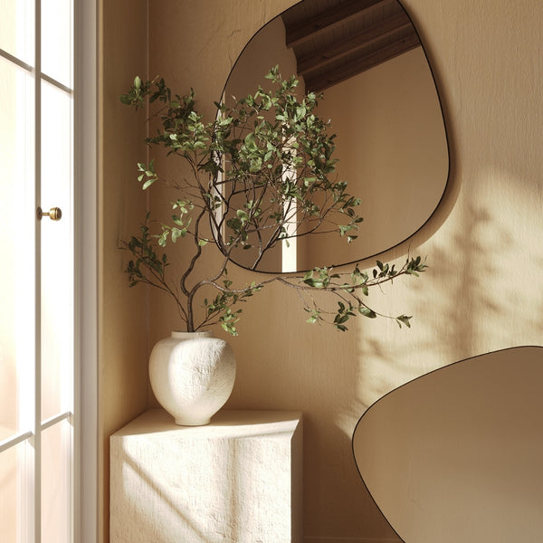 Organic blob-shaped frameless wall mirror with a soft asymmetrical silhouette, mounted on a neutral wall.