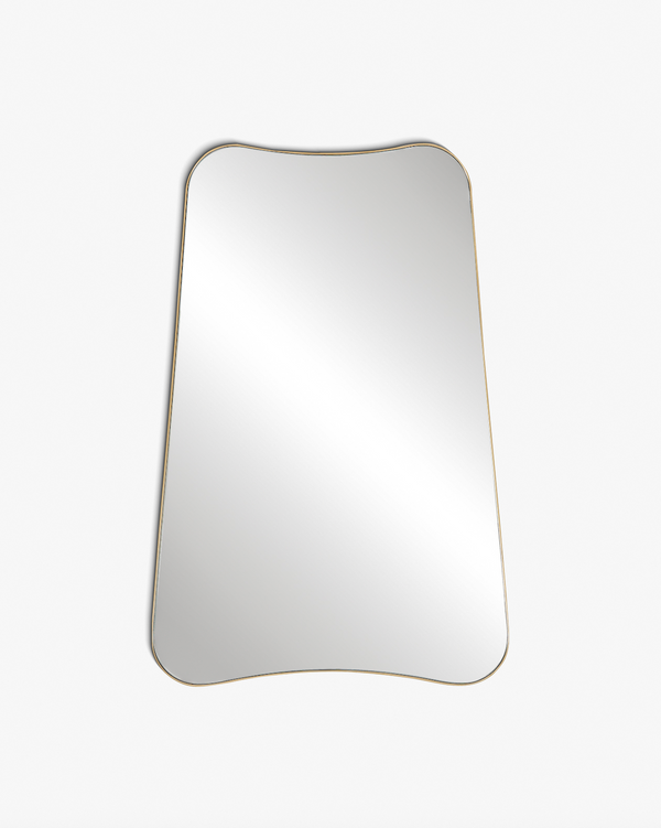 A sculptural wall mirror with softly curved edges and a slim brass frame, shown against a clean white background.