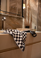 Black checkered towel draped over a bathroom sink edge.