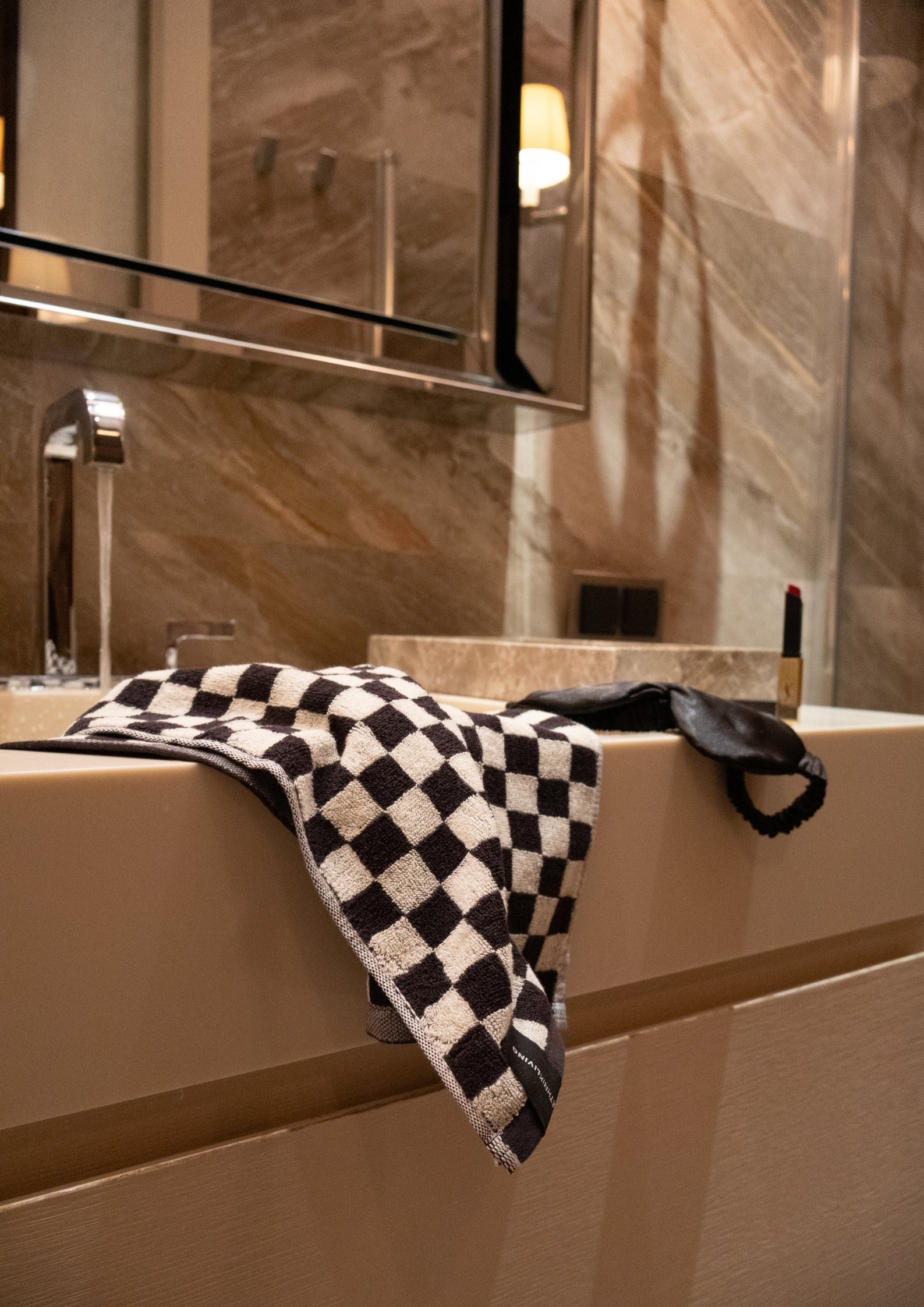 Black checkered towel draped over a bathroom sink edge.