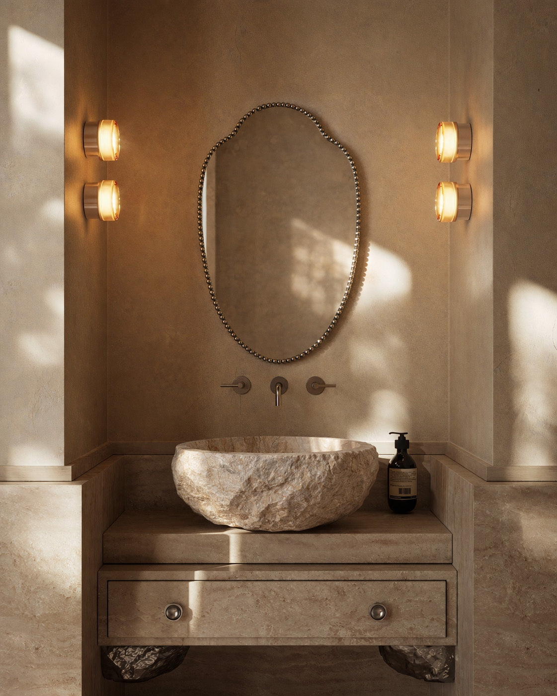 Clove Mirror with decorative beaded edge mounted above a carved stone sink and wall sconces.