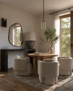 Modern dining room with wooden table, beige chairs, and large mirror on the wall.