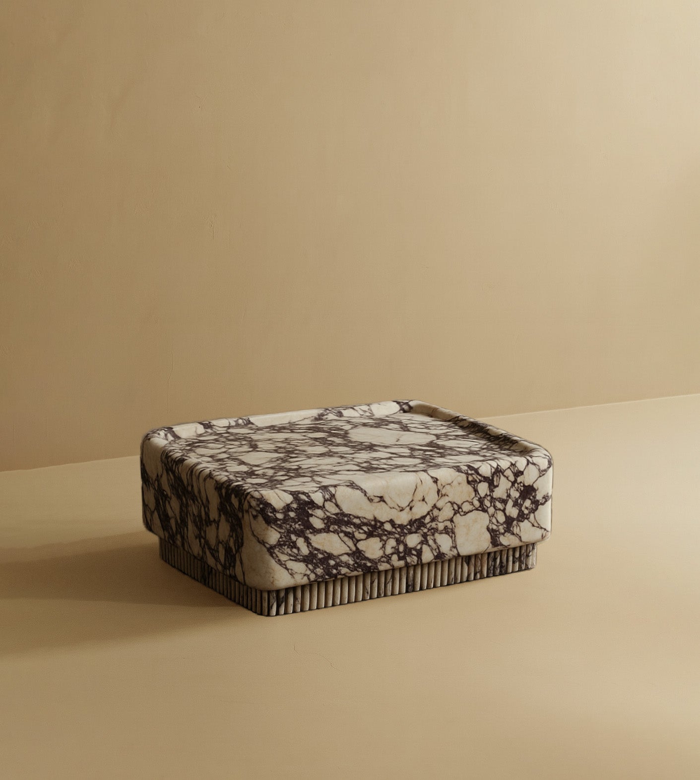 Square coffee table made from Calacatta marble, featuring bold dark veining, a solid block silhouette, and a low-profile base.