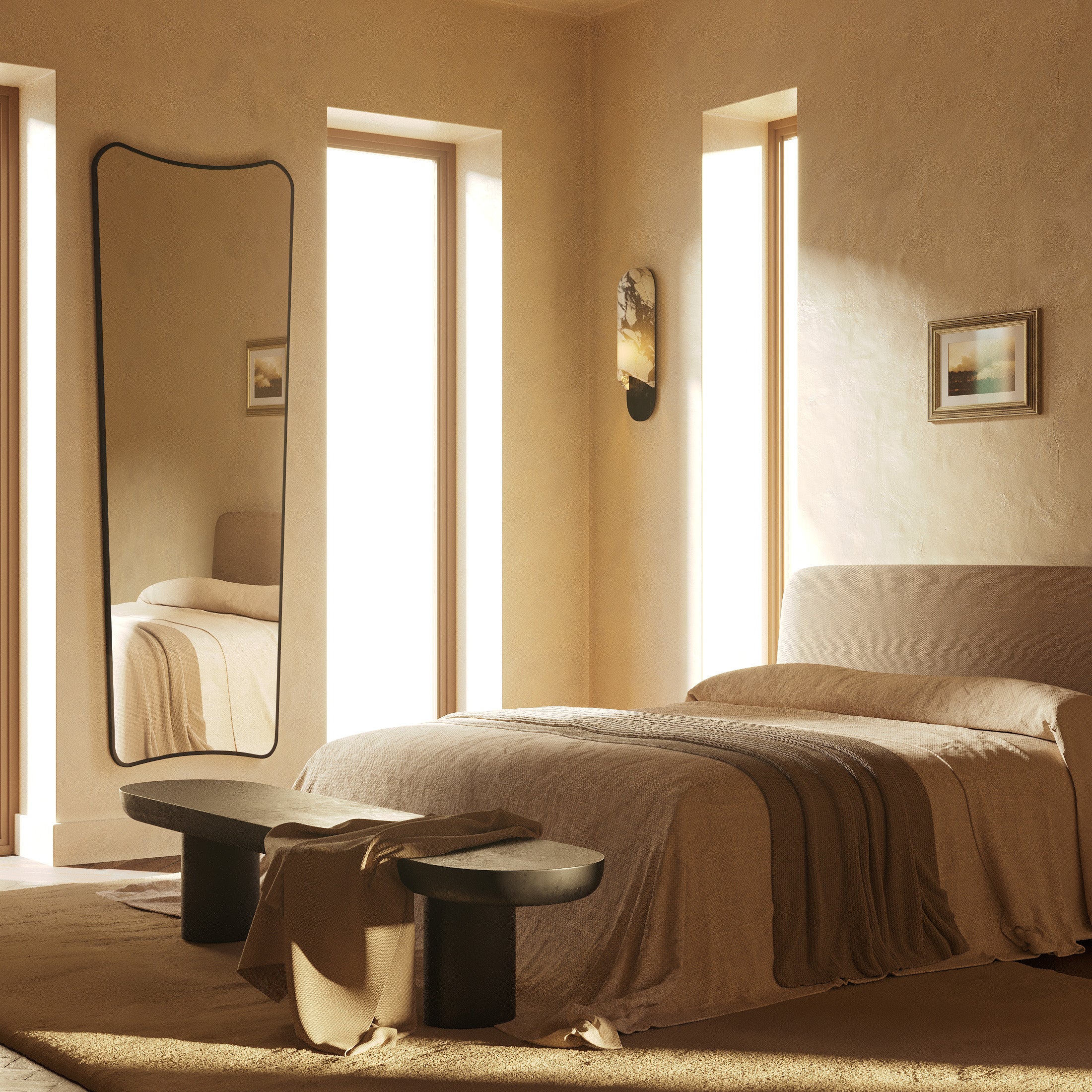 Minimalist bedroom with a low upholstered bed, textured area rug, dark wood bench, and a tall wavy-edge mirror reflecting soft natural light from narrow windows.