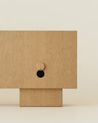 Detail view of wooden sideboard showing circular back opening and block base.