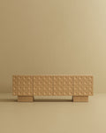 Modern wood sideboard with a grid of circular textured drawer fronts on a neutral beige background.