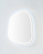 Organic-shaped LED mirror with soft cool backlit glow on a light-colored wall.