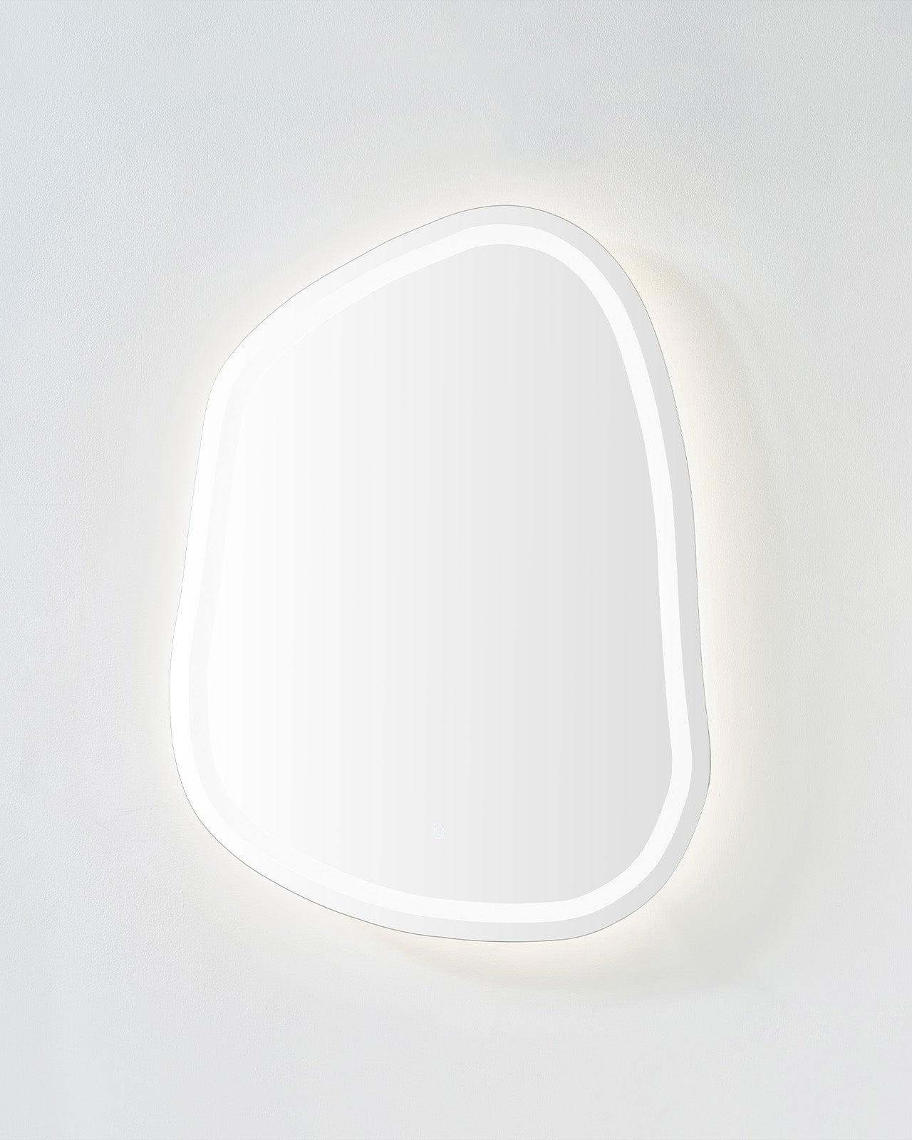 Organic-shaped LED mirror with soft neutral backlit glow on a light-colored wall.