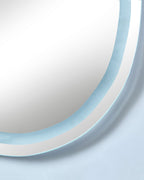 Close-up of an organic-shaped LED mirror with a cool white illuminated edge.