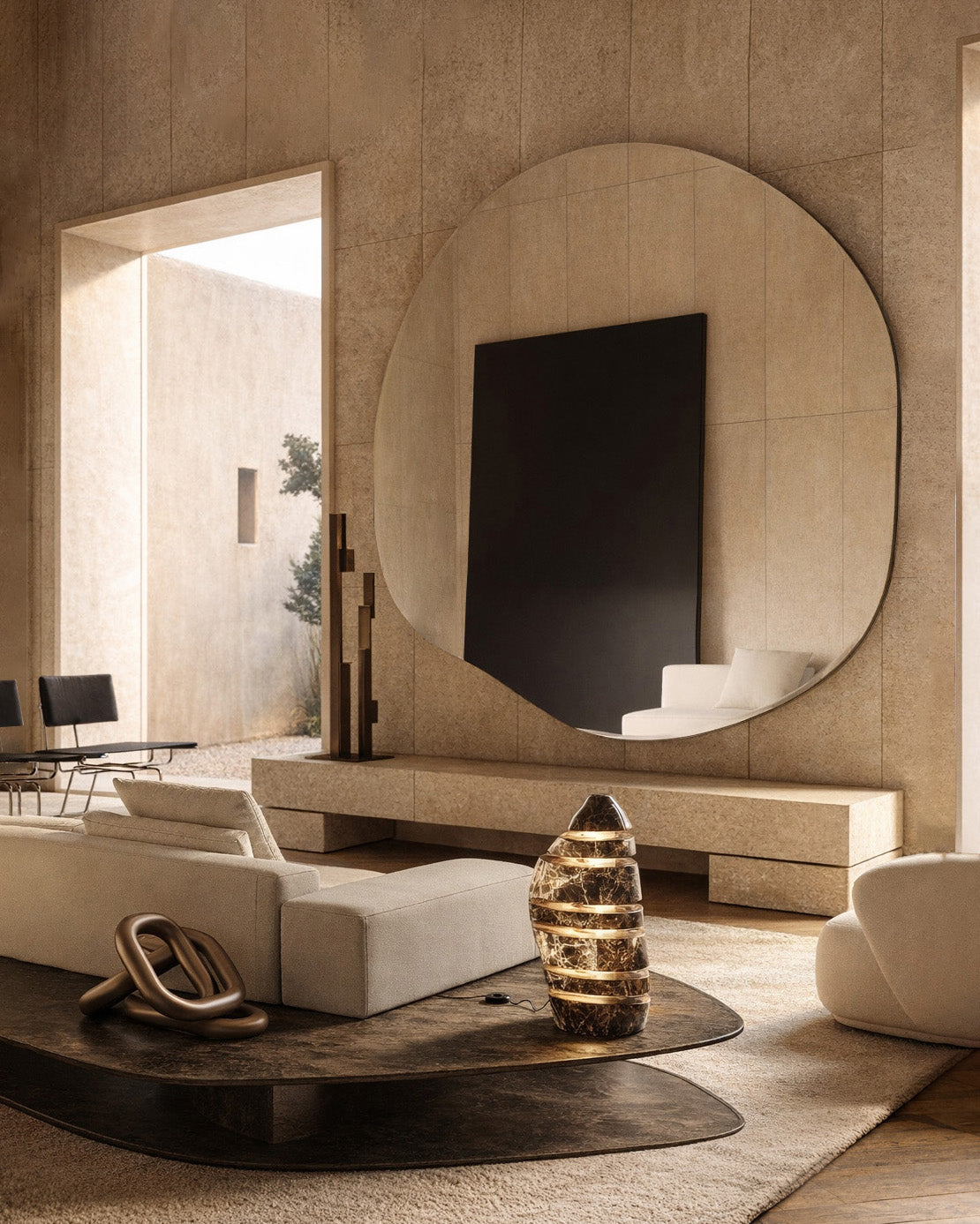 Oversized organic wall mirror above a console in a warm-toned minimalist living room.