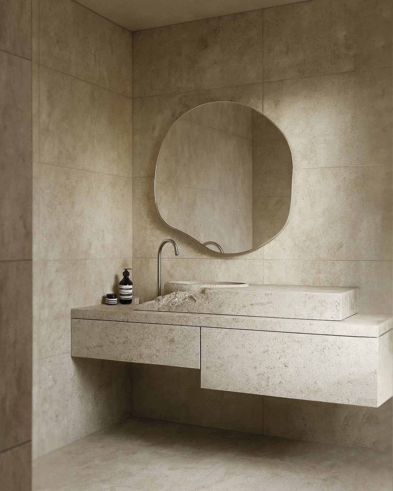 Organic-shaped wall mirror with a slim stainless steel frame mounted above a stone vanity in a minimalist bathroom.