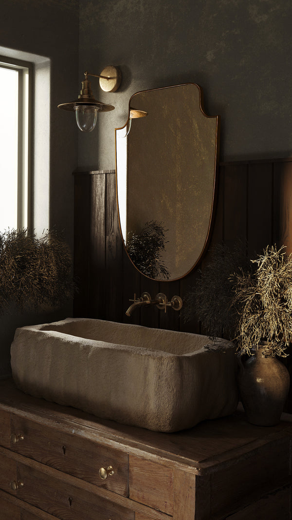 Bathroom detail showing stone sink, faucet, wall-mounted mirror, and light fixture.
