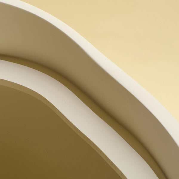 A close-up view of the rim and interior edge of a beige sculptural dustbin, photographed against a light yellow background.