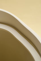 A close-up view of the rim and interior edge of a beige sculptural dustbin, photographed against a light yellow background.